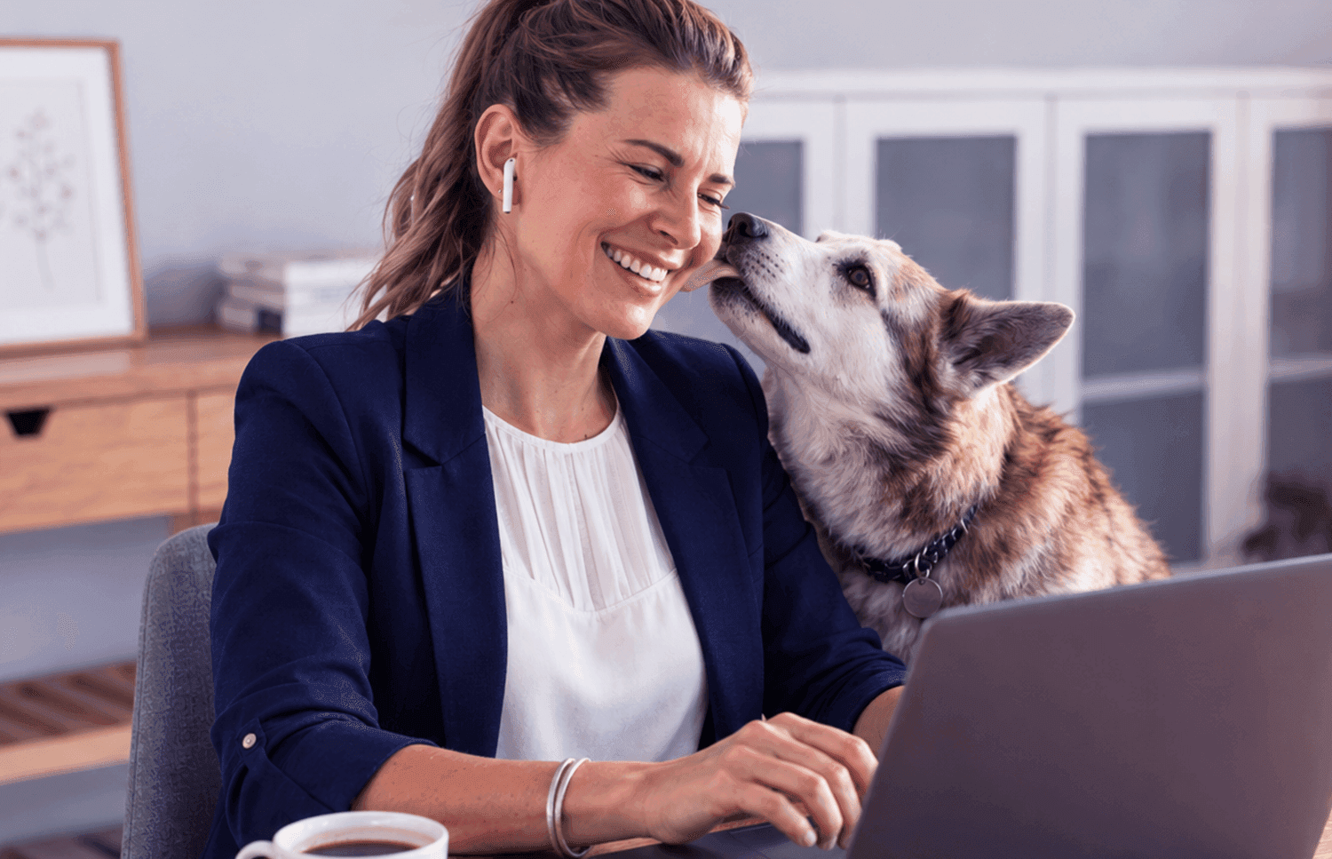 Mulher usando notebook em casa com seu cachorro ao lado